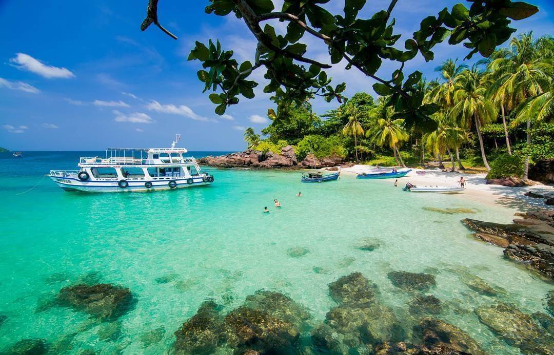 Phu Quoc beach with clear water, palm trees, and luxury resorts
