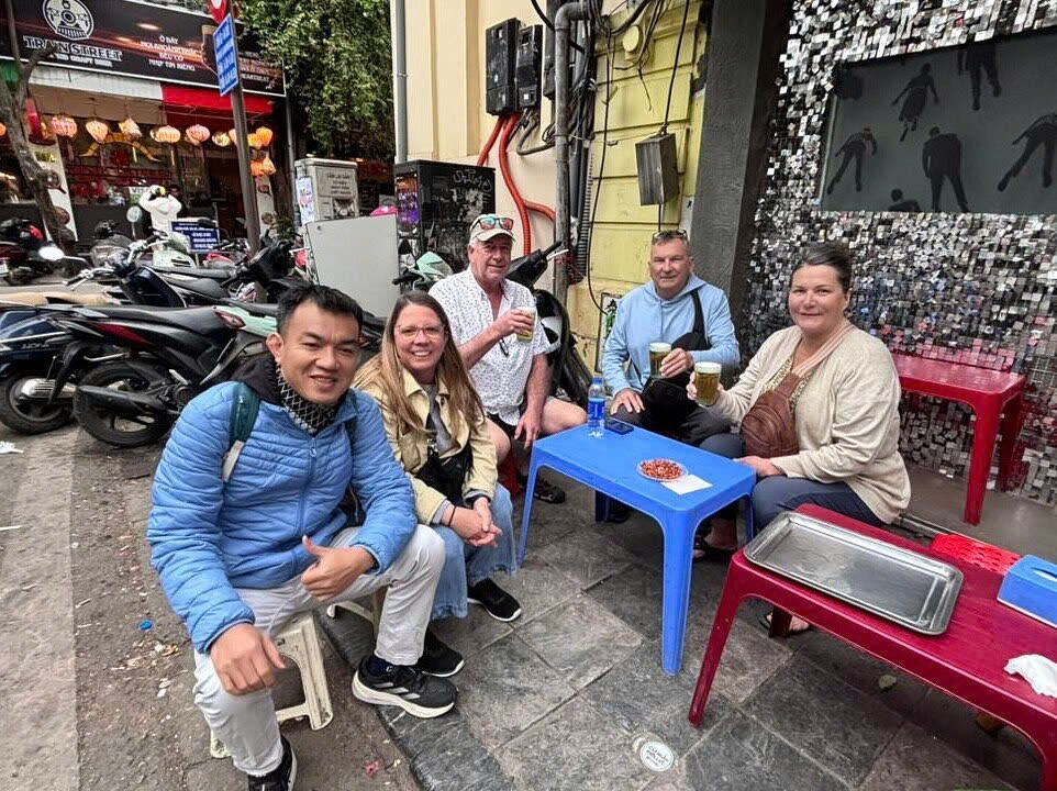 Travelers enjoying local Hanoi street food and draft beer experience with Vietnam Asia Travel in Hanoi Old Quarter.